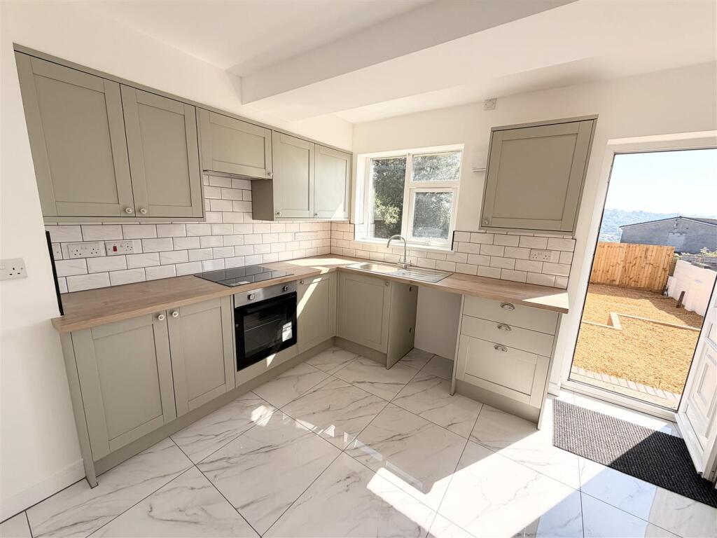 Fitted kitchen in sage shaker units with oak worktops, opening onto the garden